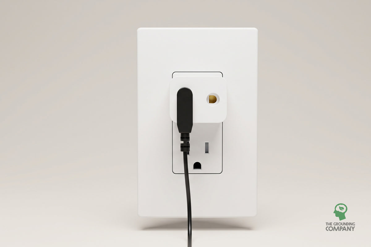 USA earth adapter plugged into a wall outlet with a grounding cord connected