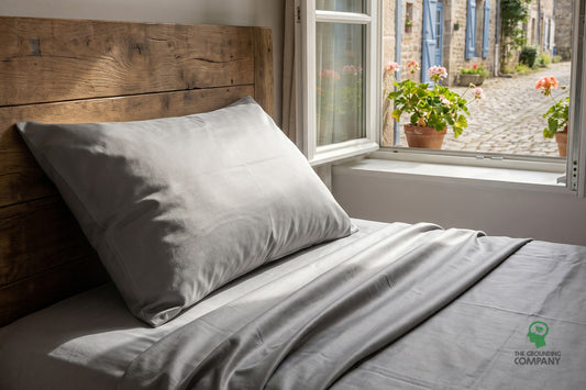 SoftSilver grounding sheet and pillowcase made up on a bed by a sunlit window