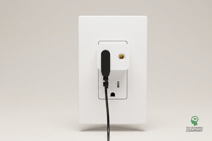 USA earth adapter plugged into a wall outlet with a grounding cord connected