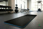 Grounding Yoga & Fitness Mat déroulé sur le sol d'une salle de sport, cordon branché sur une prise murale