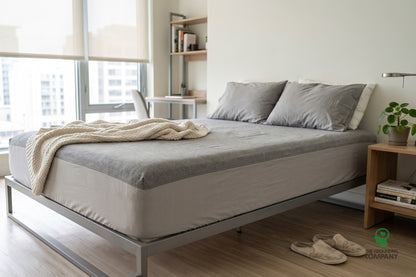 Fitted sheet on a bed, showing the grey top panel and lighter cotton side panel